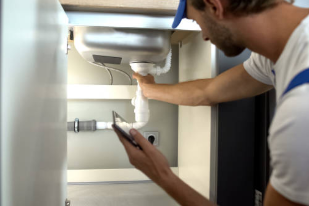 Loodgieter inspecteert en repareert de afvoer onder een keukenblad.